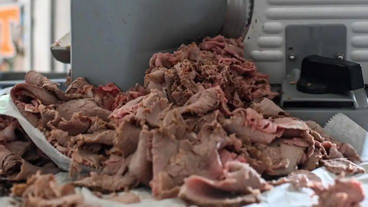 a pile of meat sitting on top of a metal table next to a machine and paper towels