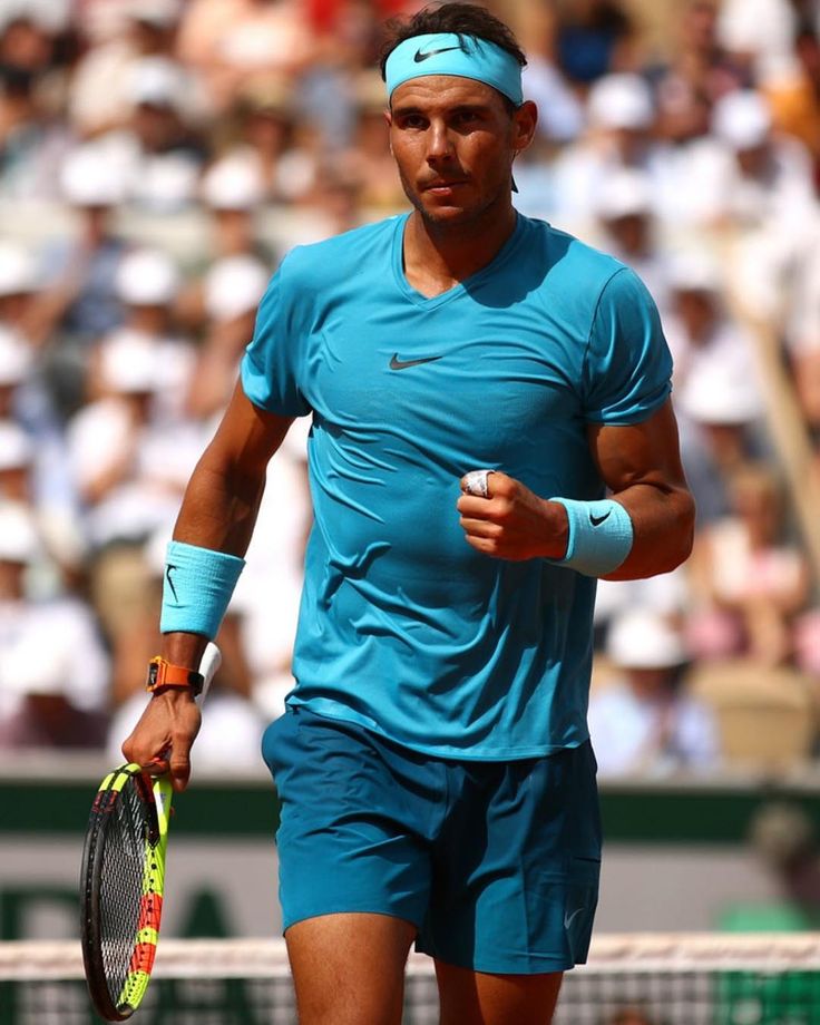 a man holding a tennis racquet on top of a tennis court with people in the background