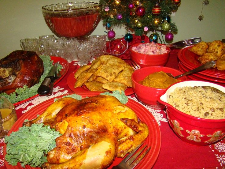 a table topped with red dishes filled with turkey and other foods next to a christmas tree