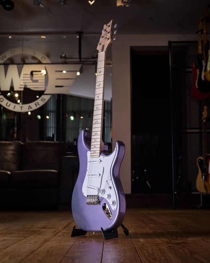 a purple guitar sitting on top of a wooden floor