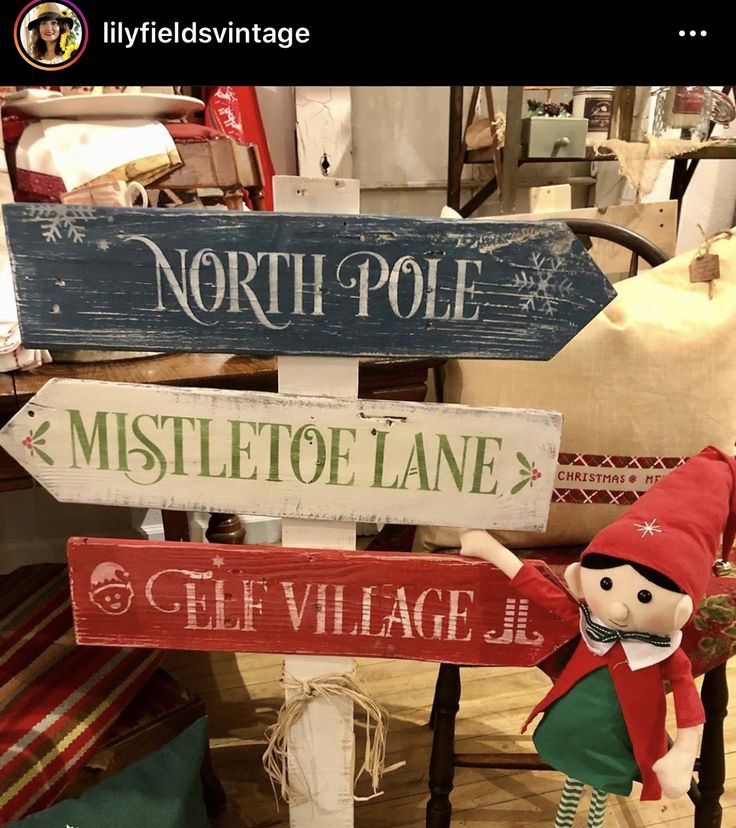 a wooden sign that says north pole, mistletoe lane and the village elf