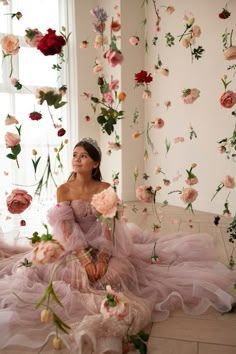 a woman in a pink dress sitting on a bench with flowers all over her body