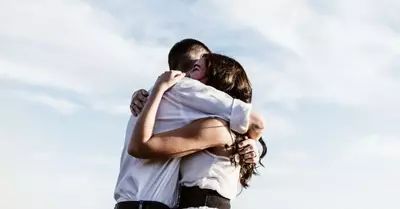 two people hugging each other in front of a blue sky