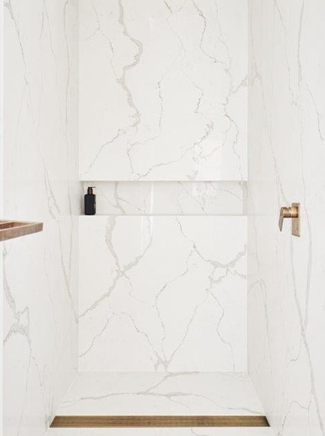 a white bathroom with marble walls and floor