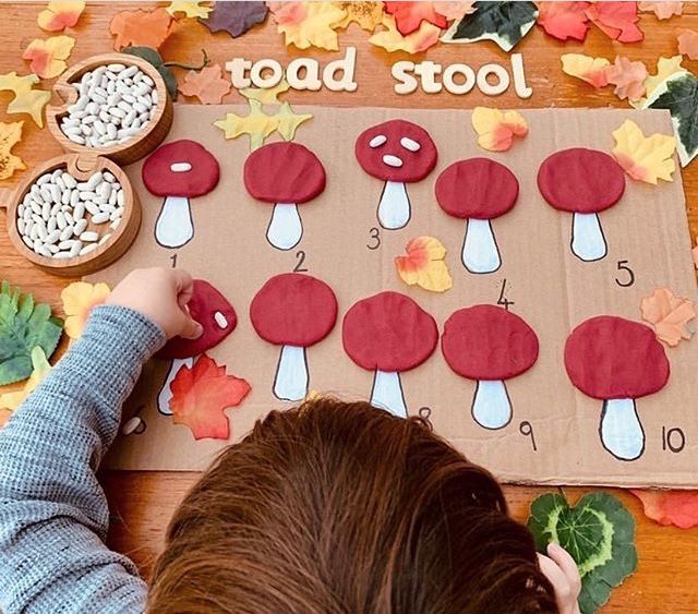 a young boy is making a mushroom craft with leaves on the ground and other autumn activities