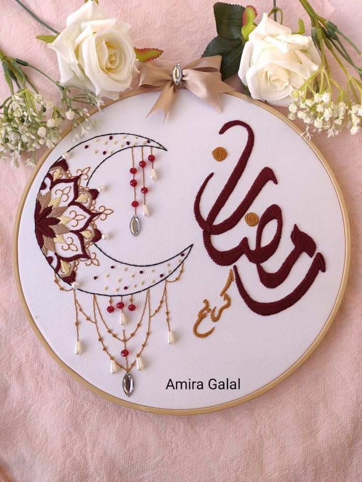 an embroidered wall hanging with the word eid written in arabic and surrounded by flowers