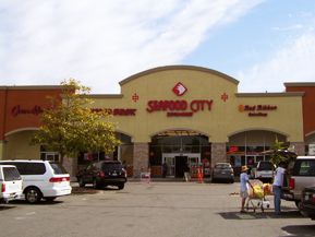 the front of a store with cars parked in front of it and people standing outside