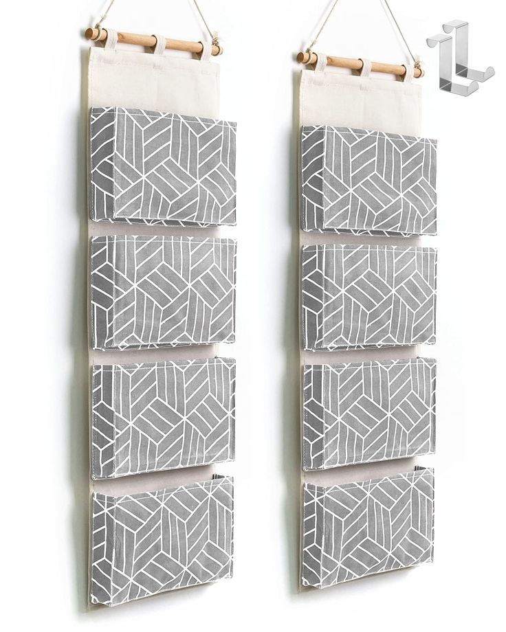 two white and gray wall hangings next to each other with hooks on the side