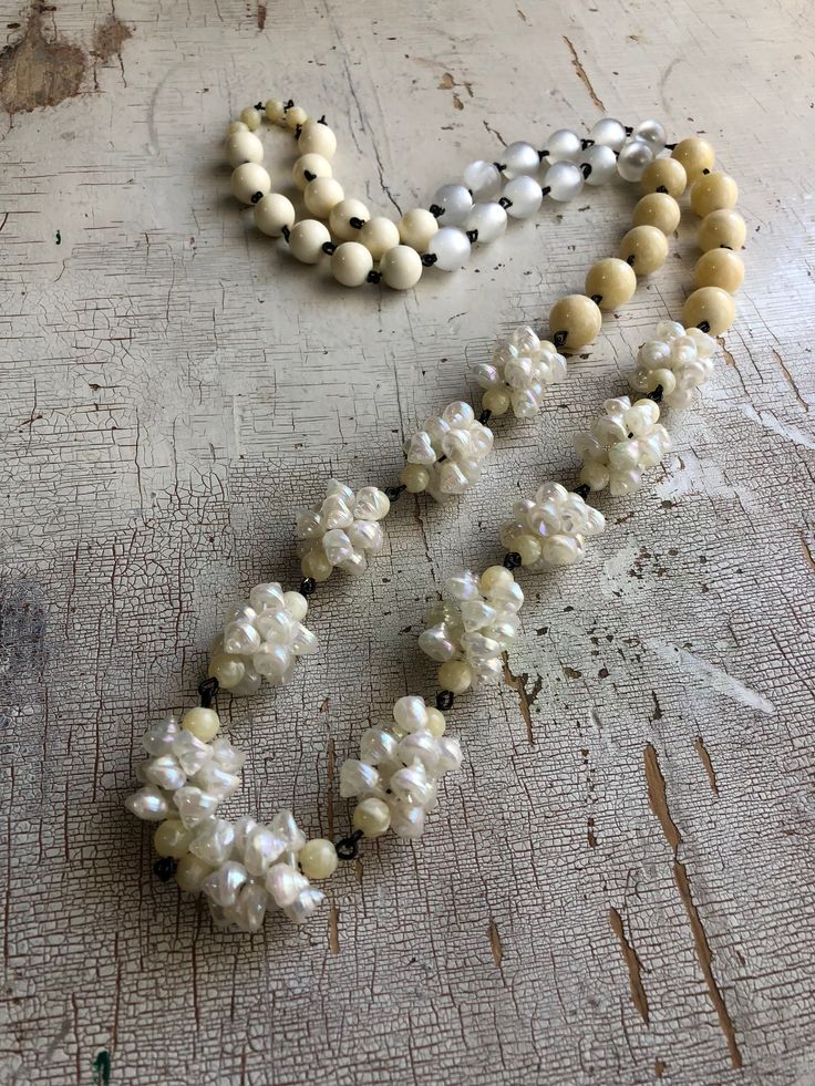 Ivory toned beaded necklace in a long Bohemian rope style, loaded with seashels & other fun cream toned beads. Beads are linked by hand with black wire chain. Necklace measures 41-44" in length & can be worn long and lean or doubled for a shorter statement look. A great versatile style. Made with lucite from 1960's deadstock, from a warehouse that closed in the early 1980's. White Multi-strand Wooden Beaded Necklaces, White Multi-strand Beaded Necklace With Wooden Beads, White Multi-strand Necklace With Wooden Beads, White Pearl Beaded Long Necklace, White Pearl Long Beaded Necklace, Adjustable Handmade Cream Pearl Necklace, Handmade Adjustable Cream Pearl Necklace, Adjustable Hand-strung White Pearl Necklace, White Single Strand Mother Of Pearl Beaded Necklaces