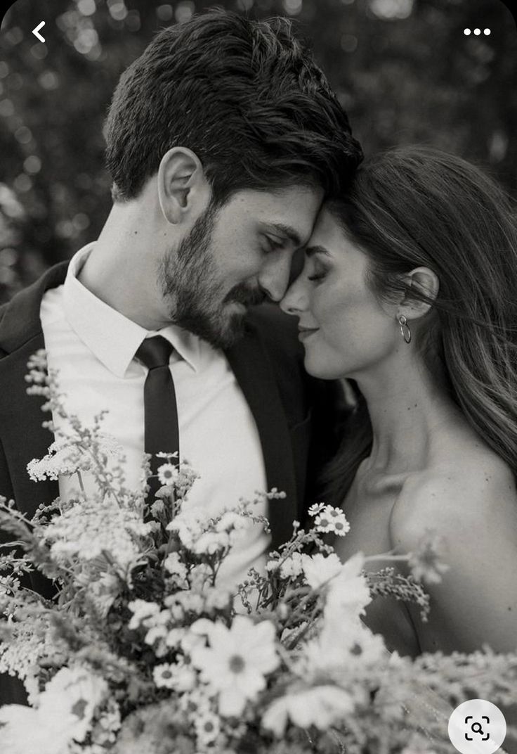 black and white photo of a bride and groom holding flowers in front of the camera