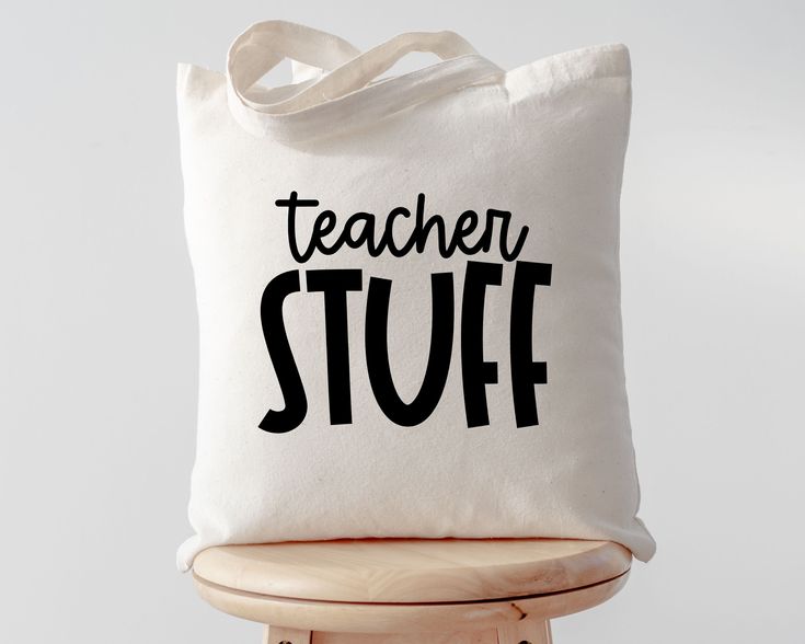 a white tote bag with the words teacher stuff on it sitting on a stool