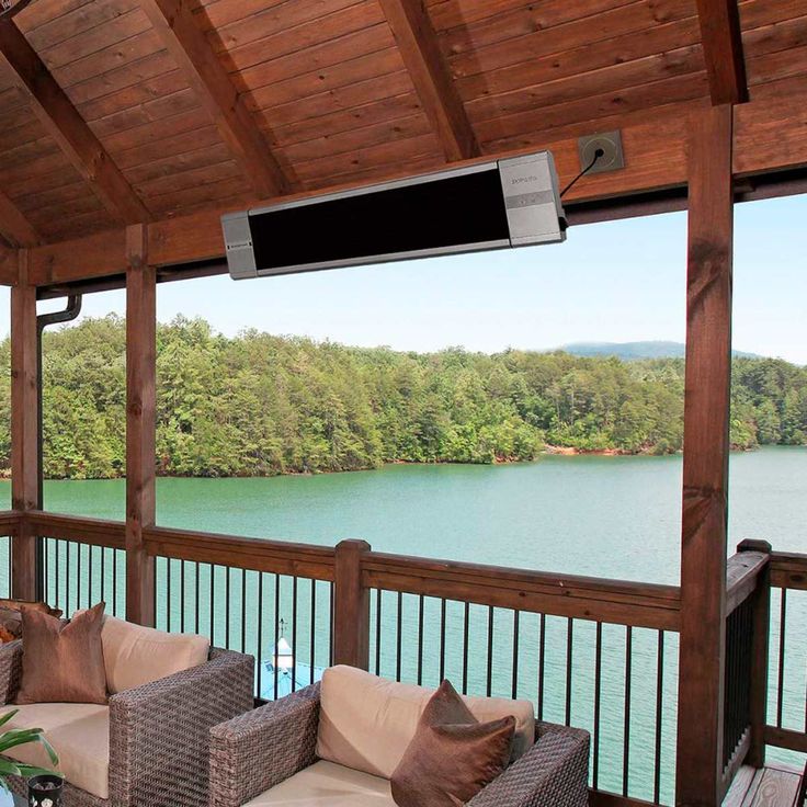 a covered porch with wicker furniture overlooks a lake