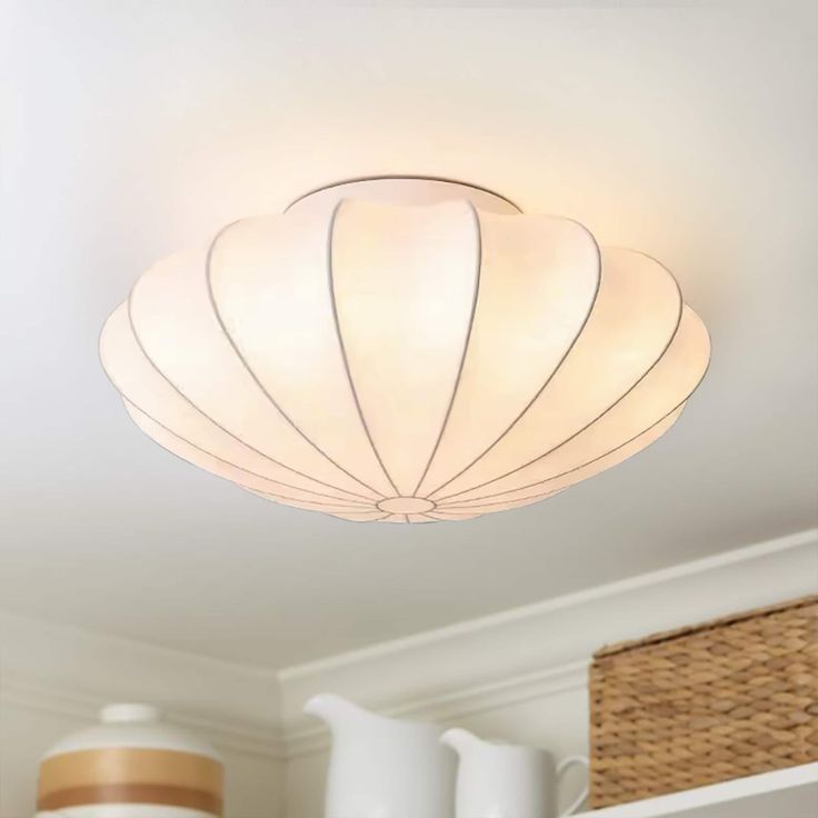 a white light fixture hanging from the ceiling in a room with wicker baskets on the floor