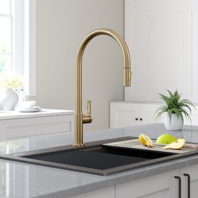 a kitchen with white cabinets and gold faucet on the counter top, next to a potted plant