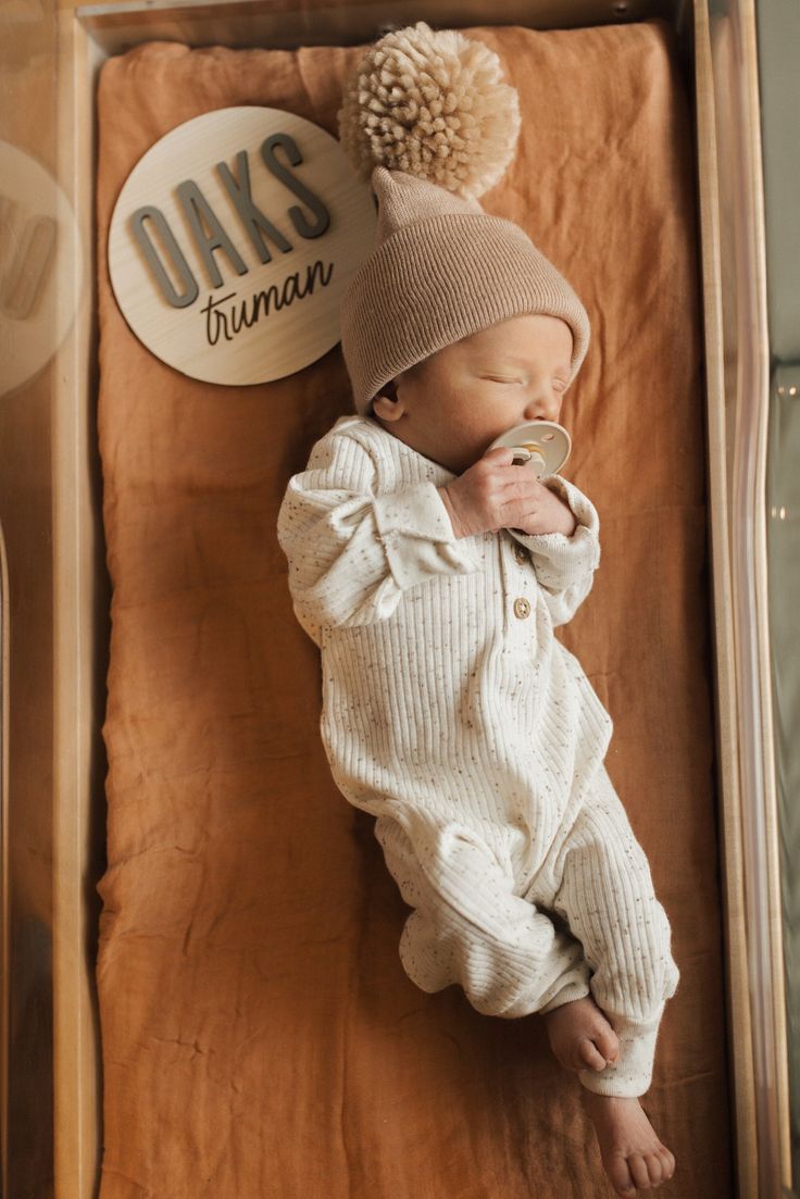 a baby is laying in a box with a hat on it's head and wearing a sweater