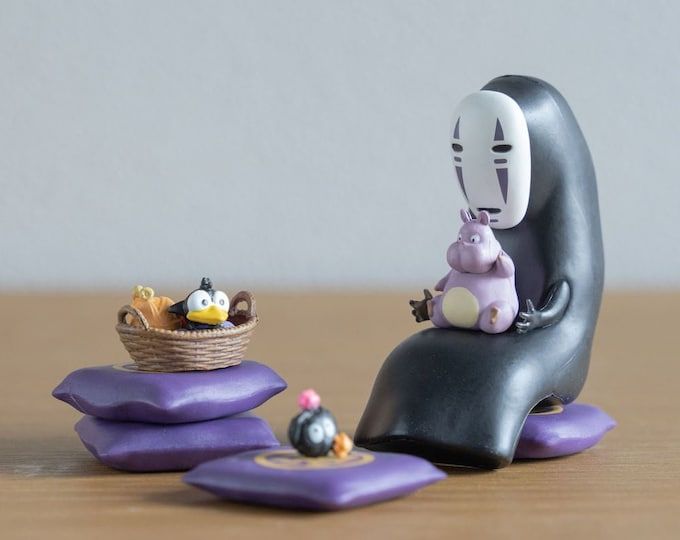 a small figurine sitting on top of a purple pillow next to a basket