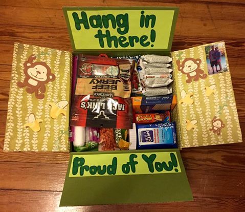 an open box with various items in it on a table next to a sign that says, hang in there proud of you