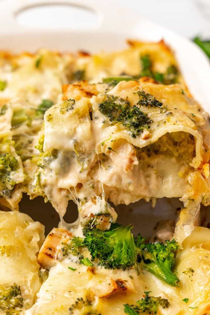 a casserole dish with broccoli and chicken is being lifted from the casserole