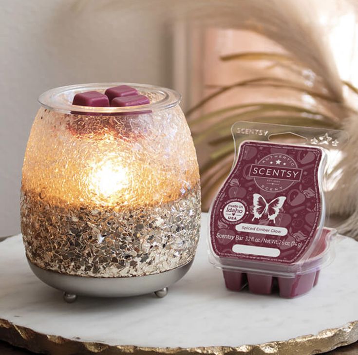 a lit candle sitting on top of a table next to a container of waxed candles