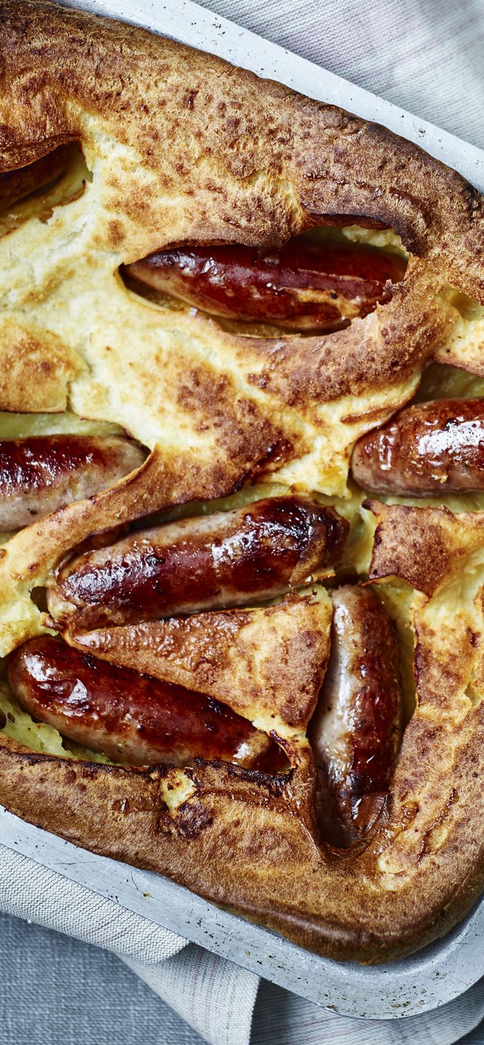 a baked dish with sausages and cheese in it on a tablecloth next to a napkin