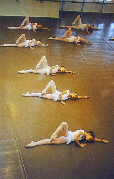 several women are laying on the floor in white leotards