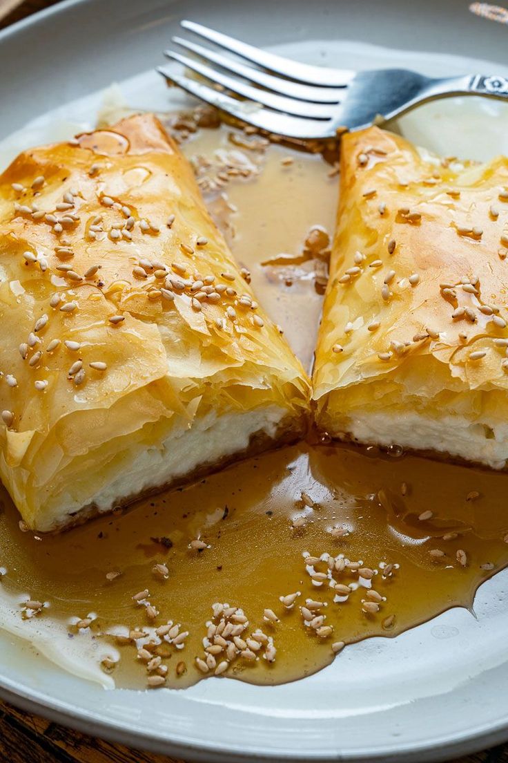 two pieces of bread are on a plate with sauce and a fork next to it