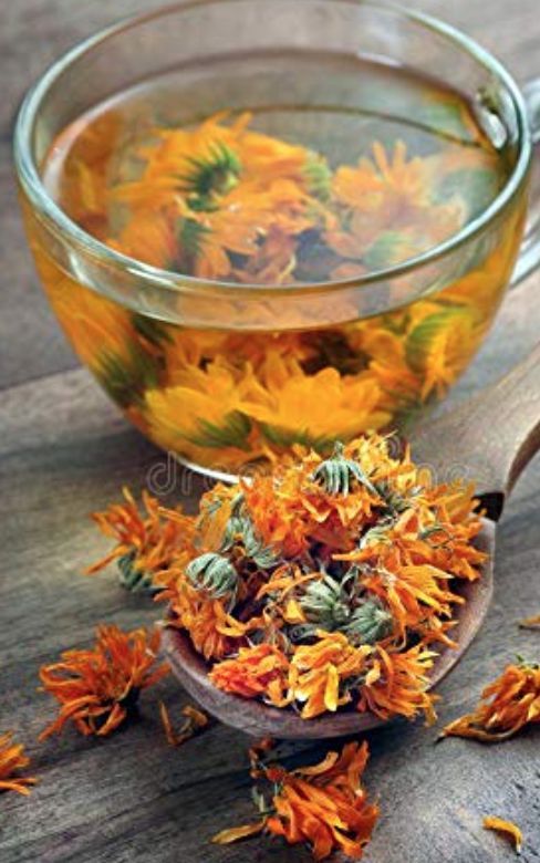 a glass cup filled with flowers next to a spoon on top of a wooden table