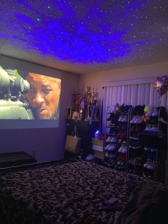 a bed room with a large screen on the wall and some shoes in front of it