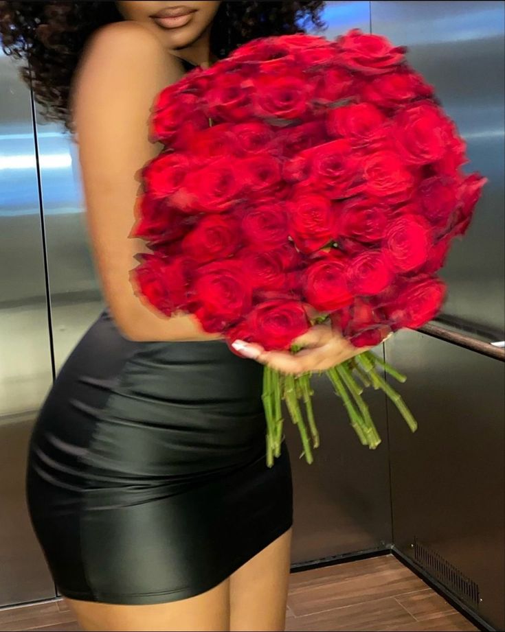 a woman holding a large bouquet of red roses