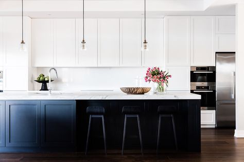 a large kitchen with white cabinets and black counter tops, along with two bar stools