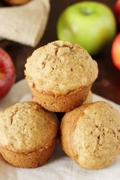 three muffins are stacked on top of each other with apples in the background