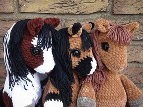 three stuffed horses sitting next to each other on a brick wall covered in yarns