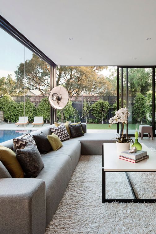 a living room filled with lots of furniture next to a large glass wall window overlooking a swimming pool