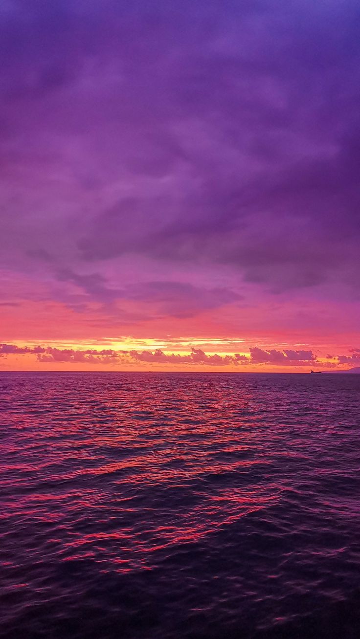 the sun is setting over the ocean with purple clouds