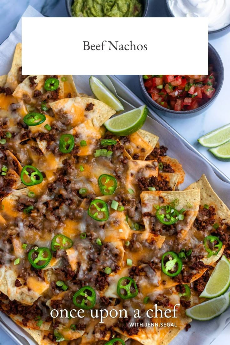 beef nachos on a tray with salsa and guacamole in the background