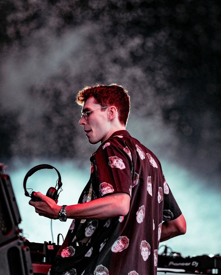 a man with red hair and glasses is holding a steering wheel while standing in front of a stage