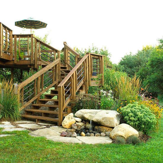 a wooden stair case next to a rock and grass garden