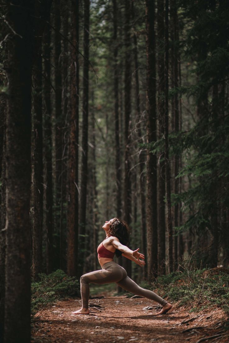 a woman is doing yoga in the woods