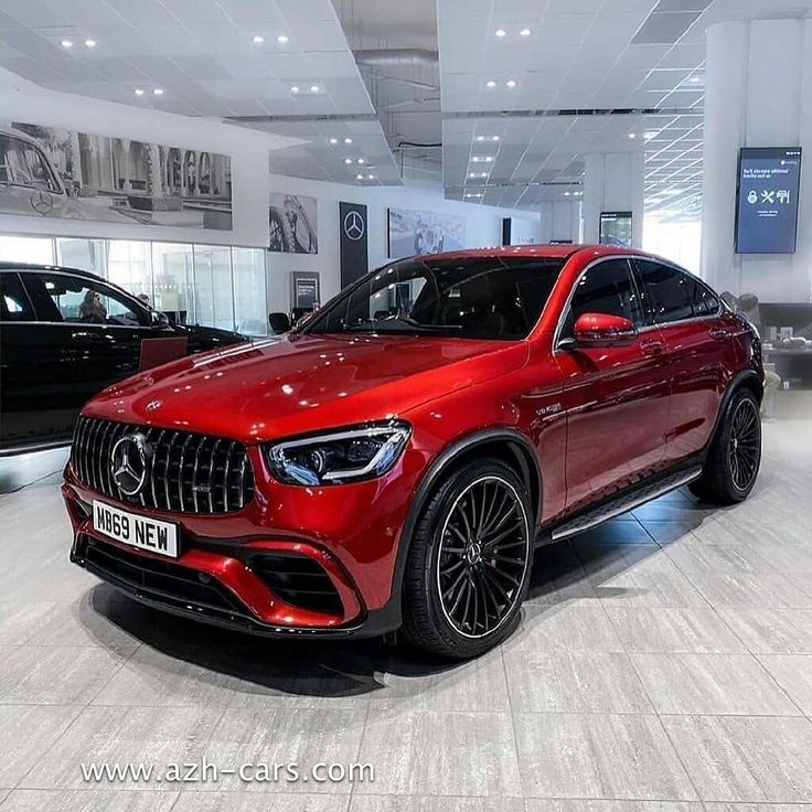 a red mercedes suv is on display in a showroom with other cars behind it