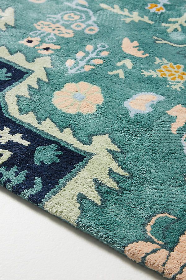 a blue rug with various flowers and animals on the top is laying on a white surface