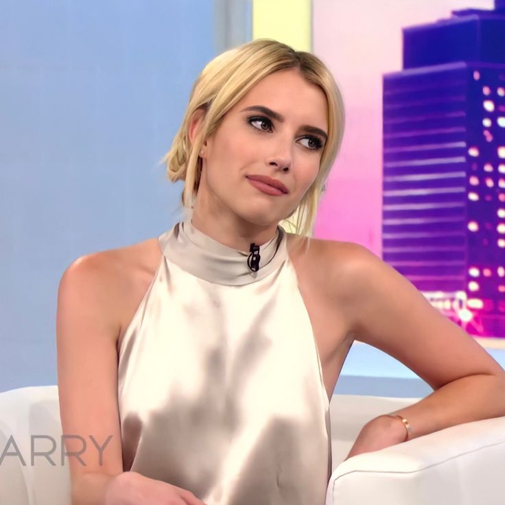 a woman sitting in a white chair with her hands on her hips and looking at the camera