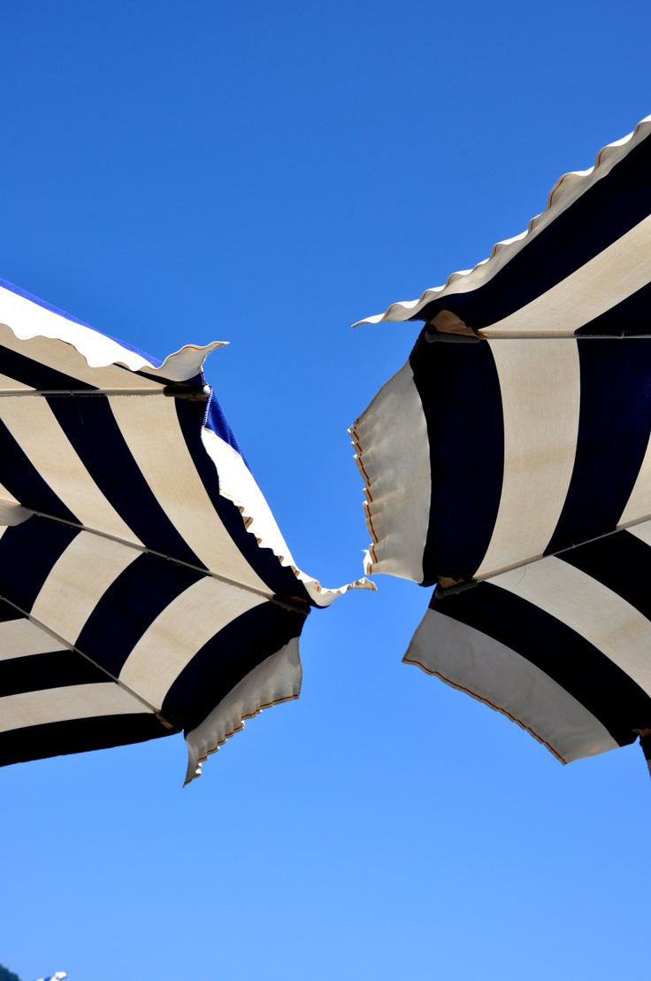 two black and white striped umbrellas against a blue sky