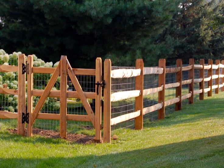 the fence is made of wood and has white flowers growing on it, along with green grass