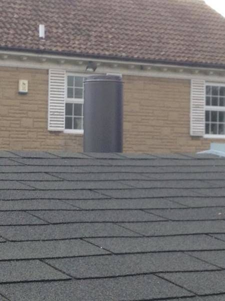 the roof of a house with two windows and a brick building in the back ground