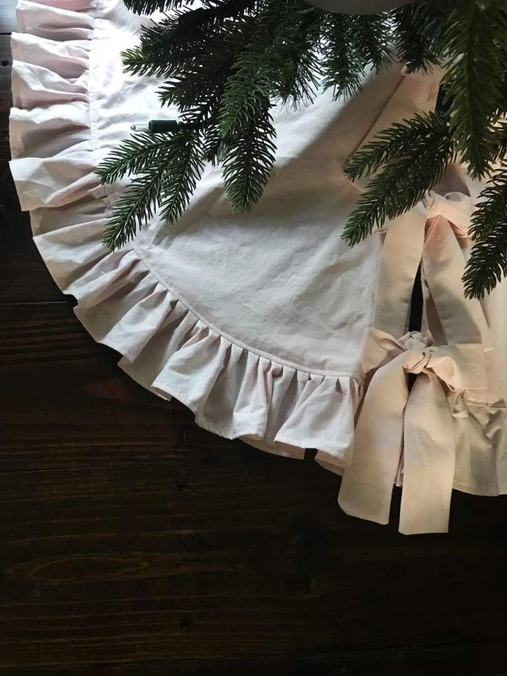 a white ruffled tablecloth with pine branches on it and ribbon around the edge