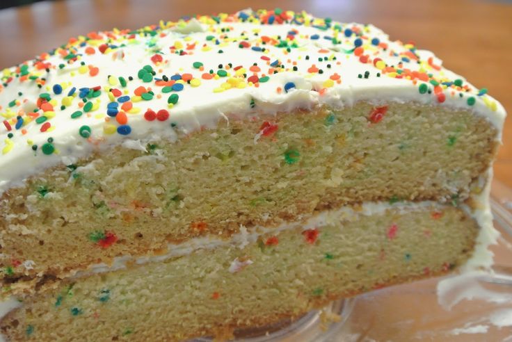 a slice of cake with white frosting and sprinkles