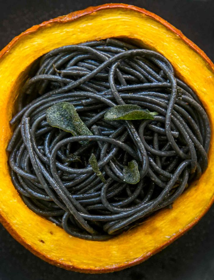 an overhead view of some black pasta in a yellow bowl