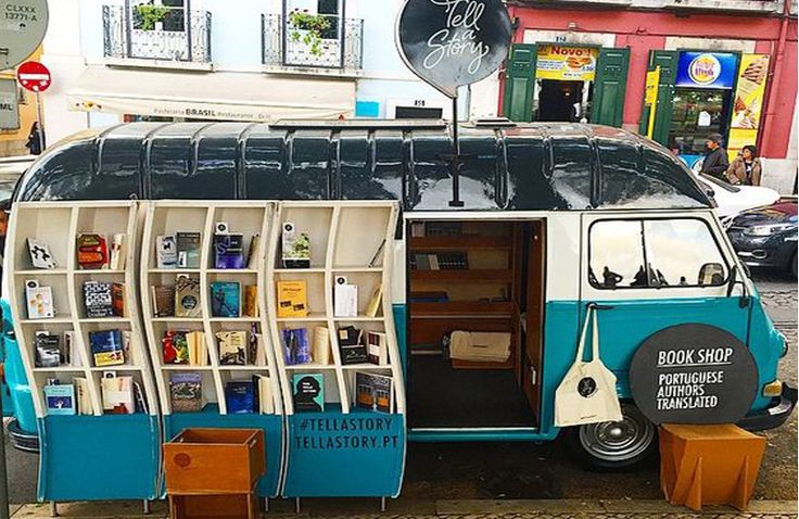 an old bus is parked on the side of the road with bookshelves attached to it