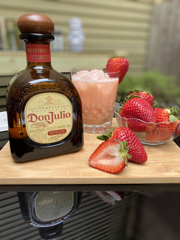 a bottle of donjuto next to some strawberries and a glass with ice