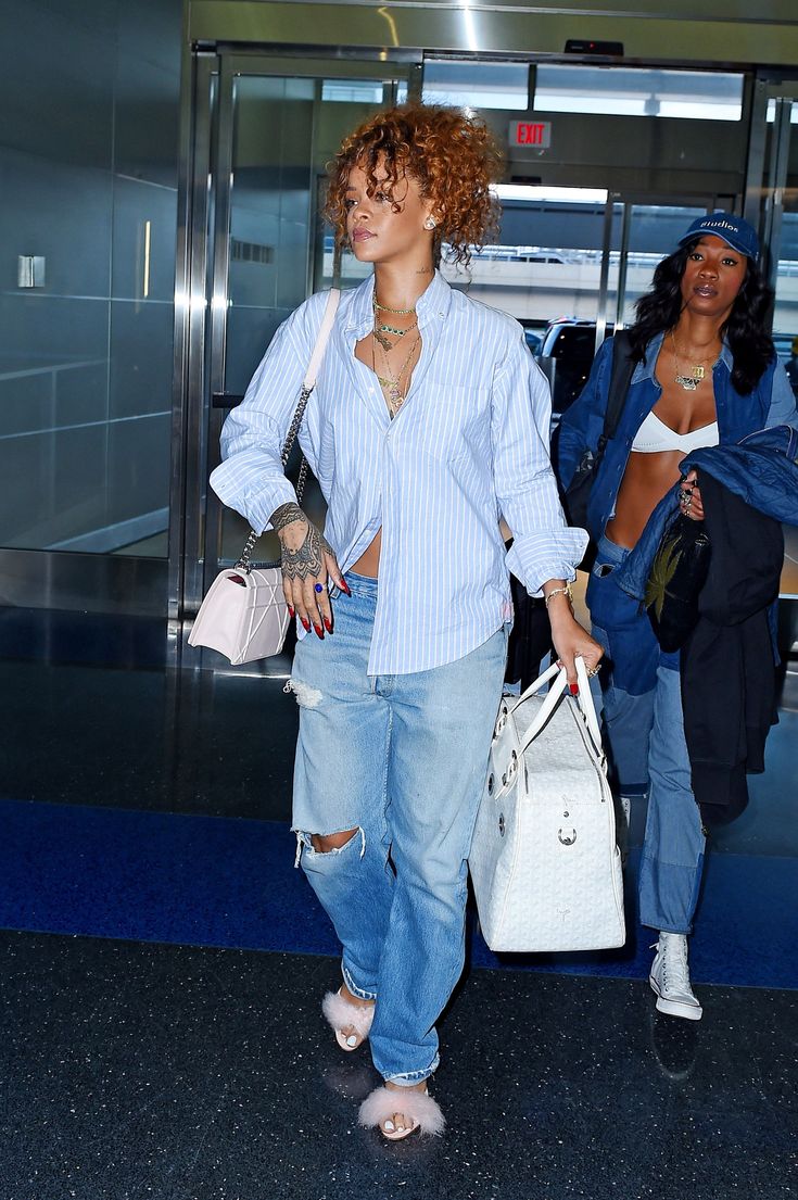 two women are walking through an airport with their purses in hand and one is wearing ripped jeans